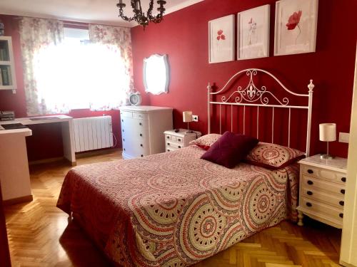 um quarto com uma cama e uma parede vermelha em Centro y playa em La Coruña