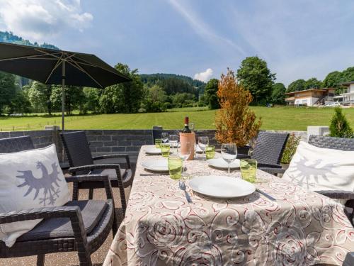 a table with wine glasses and an umbrella on a patio at Ferienwohnung Neuheim in Niederau