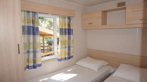 une petite chambre avec un lit et une fenêtre dans l'établissement Chalets met buitenkeuken op Camping Leï Suves - JoyCasa, à Roquebrune-sur Argens