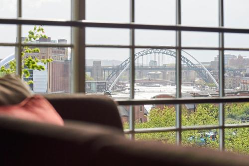 a woman sitting in a chair looking out of a window at a bridge at Hotel Du Vin Newcastle in Newcastle upon Tyne