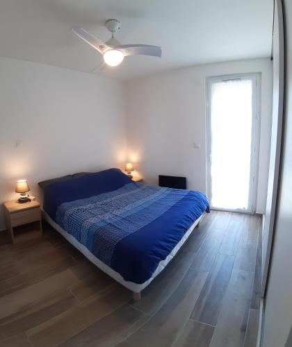 une chambre avec un lit bleu et une fenêtre dans l'établissement appartement T3 Saint-Cyprien plage, à Saint-Cyprien