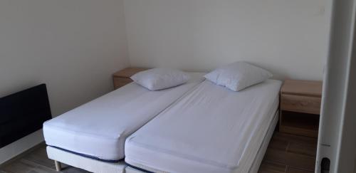 a white bed with two pillows in a room at appartement T3 Saint-Cyprien plage in Saint-Cyprien