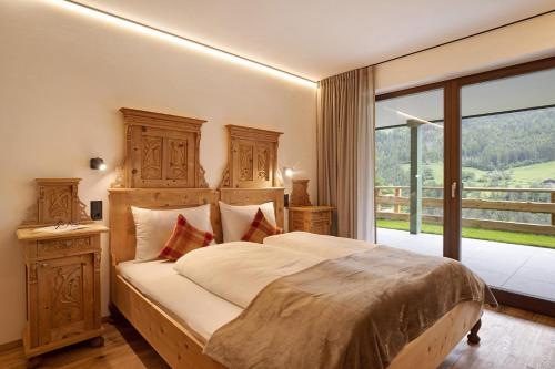 um quarto com uma cama grande e uma janela grande em Archehof Hochzirm Lodge Anton em Campo Tures