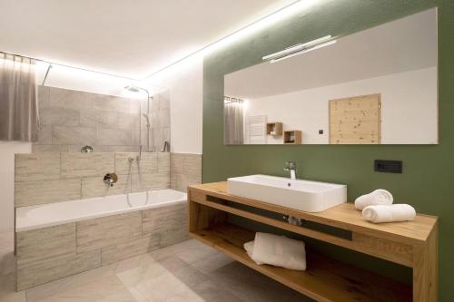 a bathroom with a sink and a tub and a mirror at Archehof Hochzirm Lodge Anton in Campo Tures