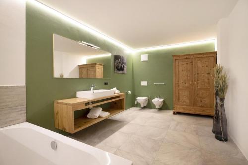 a bathroom with a sink and a mirror and a tub at Archehof Hochzirm Lodge Anton in Campo Tures
