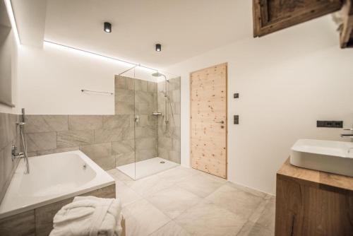 a bathroom with a shower and a tub and a sink at Archehof Hochzirm Lodge Greti in Campo Tures