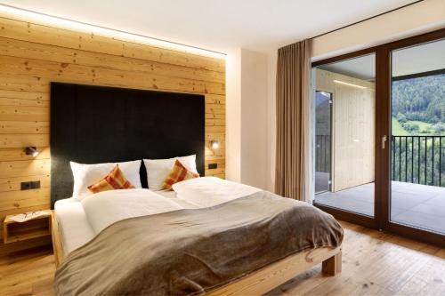 1 dormitorio con 1 cama grande y balcón en Archehof Hochzirm Lodge Anna en Campo Tures