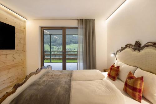 a bedroom with a large bed and a large window at Archehof Hochzirm Lodge Franz in Campo Tures
