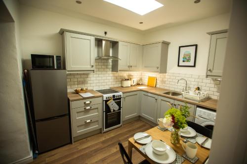 kuchnia z białymi szafkami, stołem i lodówką w obiekcie Arthur Street cottage w mieście Hillsborough