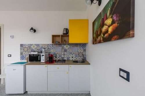 a kitchen with white cabinets and a microwave at La Scala Suite in Realmonte