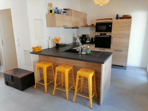 une cuisine avec un comptoir et deux tabourets jaunes dans l'établissement Le Chai de Saint-Pierre, à Saint-Pierre-dʼOléron