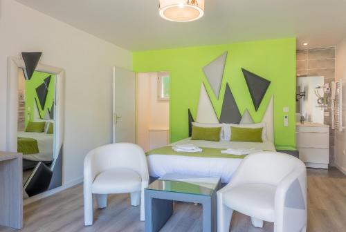 ein Schlafzimmer mit einer grünen Wand mit 2 Stühlen und einem Bett in der Unterkunft Hôtel Domaine des Pierres Dorées in Ternand