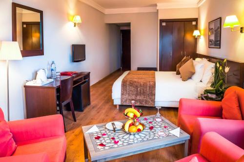 a hotel room with a bed and a table and chairs at Relax Hotel Airport Nouasseur in Nouaseur