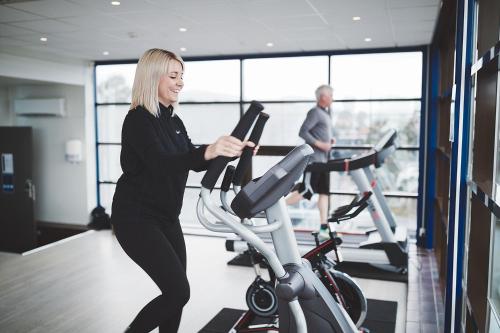a woman on an exercise bike in a gym at Stord Hotel in Stord