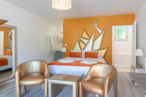 Schlafzimmer mit einem Bett mit 2 Stühlen und einem Tisch in der Unterkunft Hôtel Domaine des Pierres Dorées in Ternand