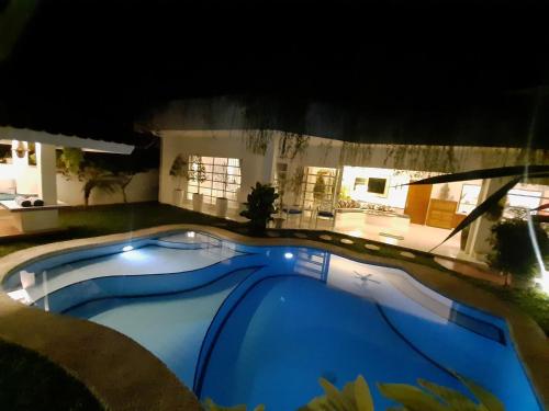 a large blue swimming pool in a yard at night at SUNKISS VILLA by Yogya Tropicana in Yogyakarta