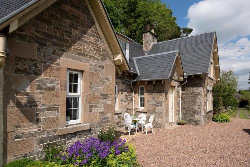 a stone house with two chairs and a table outside at Willowherb and Foxglove Cottages Hawick in Hawick