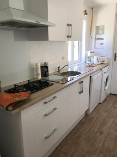 a kitchen with white cabinets and a stove top oven at La Ferme des Cailletiers chez Marco in Lucéram