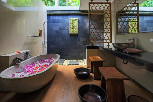 a bathroom with a large tub filled with sprinkles at Full Moon Villa Ubud in Ubud