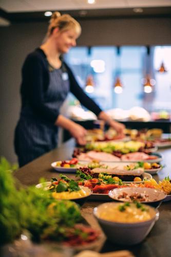 a woman standing in a kitchen with many plates of food at Stord Hotel in Stord