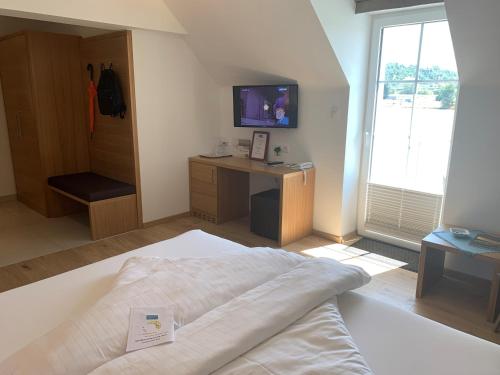 a bedroom with a bed and a desk and a television at Hotel Donauhof in Emmersdorf an der Donau