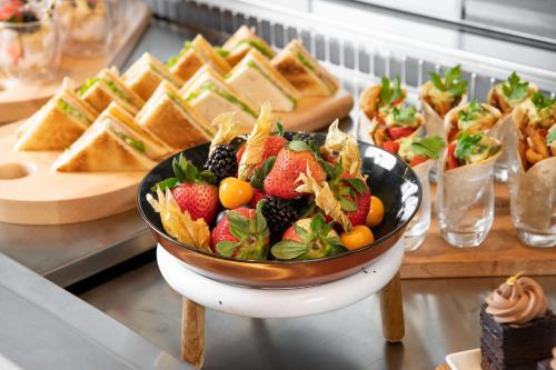 a bowl of fruit on a table with sandwiches and bread at Park Inn by Radisson, Riyadh in Riyadh