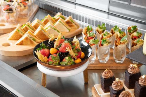 a buffet with a bowl of fruit and sandwiches and desserts at Park Inn by Radisson, Riyadh in Riyadh