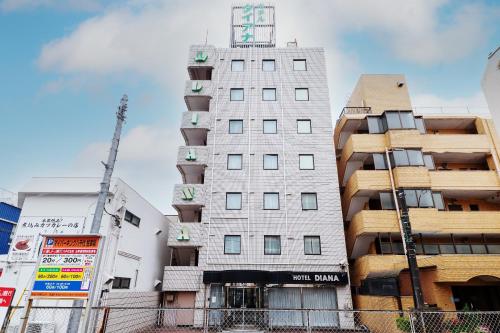 ein hohes weißes Gebäude inmitten von Gebäuden in der Unterkunft Tabist Hotel Diana Yachiyodai in Ōwada