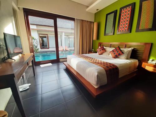 a bedroom with a large bed and a pool at Gaing Mas Jimbaran Villas by Gaing Mas Group in Jimbaran