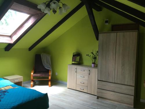 1 dormitorio con paredes verdes, 1 cama y ventana en Agroturystyka Pod Dębami w Klukach, en Smołdzino