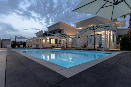 a swimming pool in front of a building with an umbrella at La Scala Suite in Realmonte
