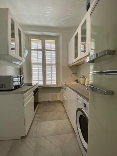 une cuisine avec des armoires blanches et une laveuse et une sécheuse dans l'établissement Beautiful Apartment 2mn walking distance from La Croisette and The Beach, à Cannes