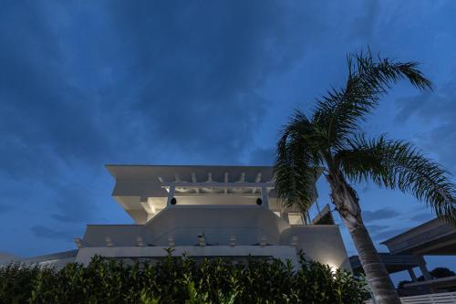 a white building with a palm tree in front of it at La Scala Suite in Realmonte