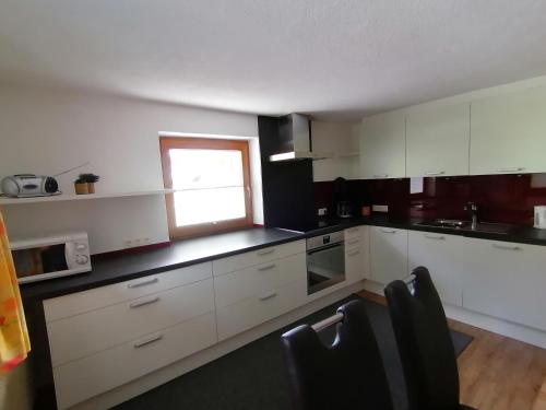 a kitchen with white cabinets and a window at Ferienhaus ANDREA in Ramsau im Zillertal