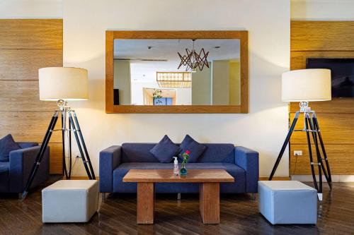 a living room with a blue couch and two lamps at Ramada Addis, Addis Ababa in Addis Ababa