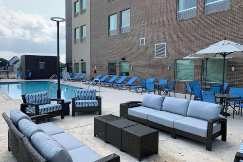 a patio with couches and chairs next to a pool at La Quinta Inn & Suites by Wyndham Round Rock near Kalahari in Round Rock