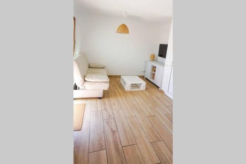 a living room with white walls and wooden floors at Apartamento recien reformado en centro a tres minutos de la playa in Corralejo