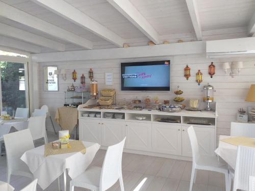 a kitchen with a television on a wall with tables and chairs at Falli Exclusive Rooms and Breakfast -Boutique B&B- in Porto Cesareo