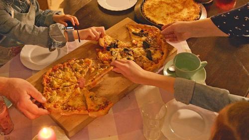 Põnka Guesthouse في Jõesuu: مجموعة من الناس يأكلون البيتزا على طاولة
