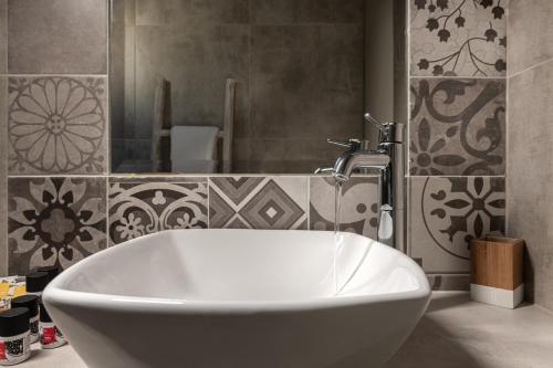 a white bath tub in a bathroom with tiles at Argo Boutique Hotel in Naxos Chora