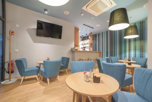 a restaurant with blue chairs and tables and a tv at Hotel Traffic Wrocław Stare Miasto in Wrocław