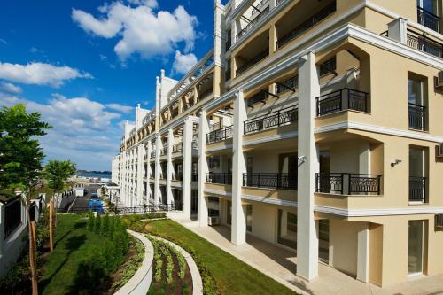 an apartment building with white columns and a street at Penelopa Palace Apart Hotel & SPA in Pomorie