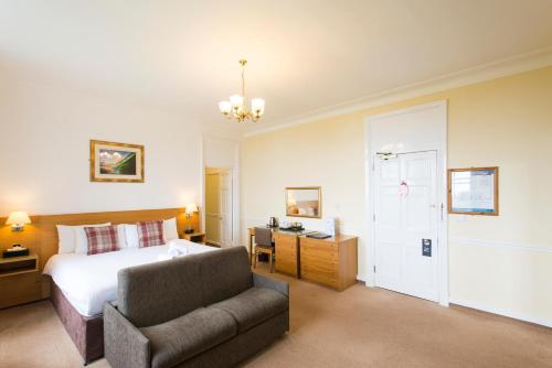 a bedroom with a bed and a couch and a chair at Tregenna Castle Resort in St Ives
