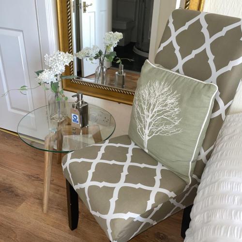 a chair with a pillow on it next to a glass table at Beechwood Ensuite Guest House in Ayr