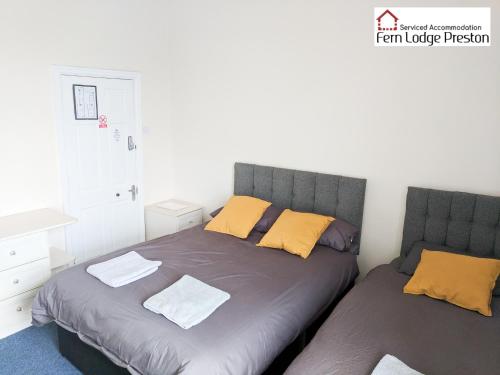 a bedroom with two beds with yellow pillows at 4 Bedroom House at Fern Lodge Preston Serviced Accommodation - Free WiFi & Parking in Preston