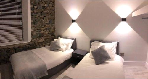 a bedroom with two beds and two lights on the wall at Lisvarna House in Buncrana