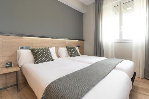 a bedroom with two beds and a window at Alda Centro Pamplona in Pamplona