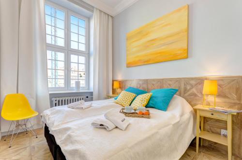 - une chambre dotée d'un grand lit avec des oreillers bleus et jaunes dans l'établissement Dom & House - Old Town Mariacka, à Gdańsk