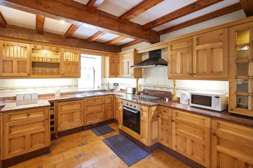 a kitchen with wooden cabinets and a stove top oven at Host & Stay - The Cottage Barn in Skipton