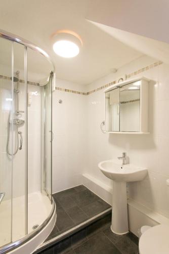a white bathroom with a sink and a shower at Tregenna Castle Resort in St Ives